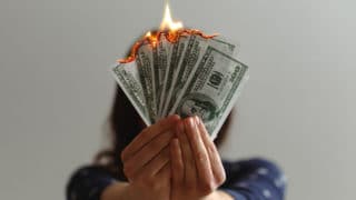 Close up of woman's hands holding burning one-hundred dollar bills