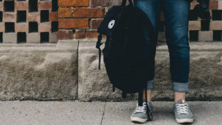 student holding backpack by leg