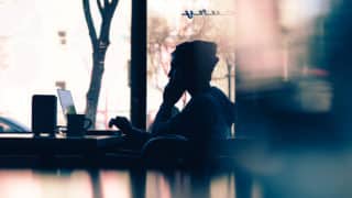 Silhouette of person working on laptop in coffee shop